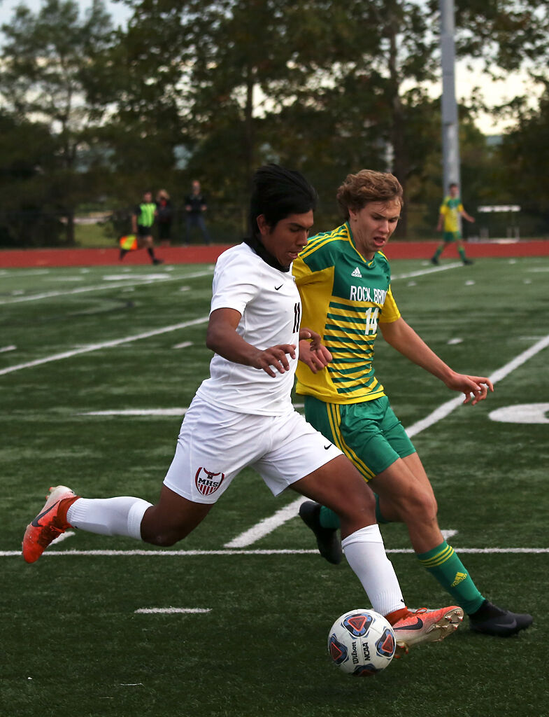 Marshall senior Sergio Ruiz kicks the ball down the pitch while Rock Bridge senior Wesley Goyette chases him